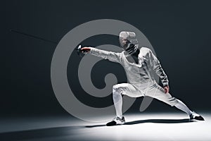 Professional fencer in fencing mask with rapier standing in position