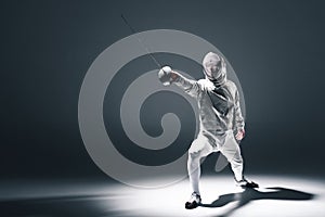 Professional fencer in fencing mask with rapier standing in position photo