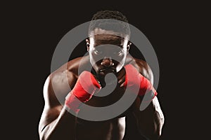 Professional fighter in boxing stance posing over black studio background