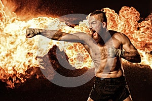 Professional fighter shadowboxing with fire and sparks on background