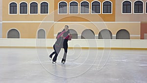 Professional figure skating coach explaining girl on skate how to move, taking her hand and showing right position jump