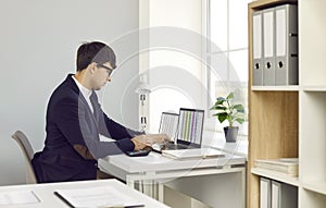 Professional financial accountant working on laptop computers at his office desk