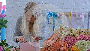 Professional florist making gift box with flowers at flower store