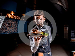 Professional flunky helpfully serves cooked dish at a festive event.