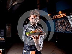 Professional flunky helpfully serves cooked dish at a festive event.