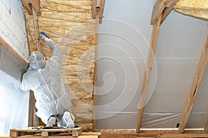 Professional foreman installing thermal insulation rock wool under the roof