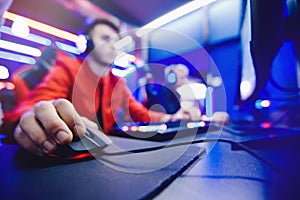 Professional gamer controls computer mouse online game in neon color blur background, soft focus