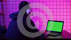 Professional Gamer Playing Video Game on His Laptop. Green Screen Mock-up Display.