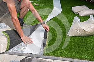 Professional gardener is cutting artificial turf to fit