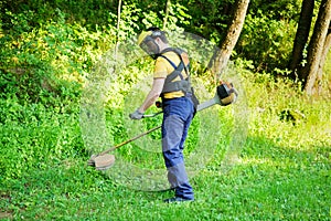 Professional gardener using an edge trimmer in home garden