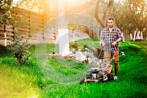 Professional gardener using lawn mower and cutting grass during summer sunset