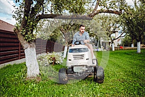 Professional gardener using lawn tractor for mowing grass in garden