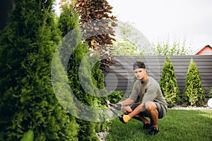 Professional Gardener at Work. Gardener Trimming Garden Plants. Topiary Art.