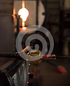 Professional glass blower holding glass mold with high heat fire for shaping