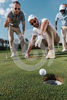 Professional golf players looking at ball near the hole