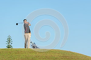 Professional golfer asian man approach on the tee off for swing and hitting golf ball and looking fairway in course. Hobby in holi