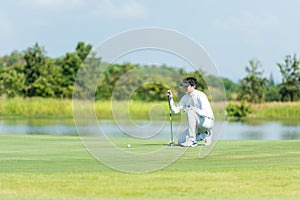 Professional Golfer asian man playing aiming shot for putting ball on the hole with club on green course.  Hobby in holiday and va