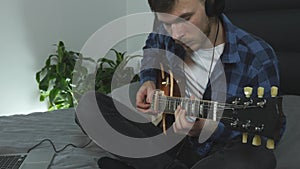 Professional guitar teacher playing on electric guitar. Young man in headphones performs his new lyric song. Male guitarist plays