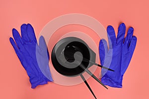 professional hair coloring kit, bowl, brushes, combs and rubber gloves on a pink background