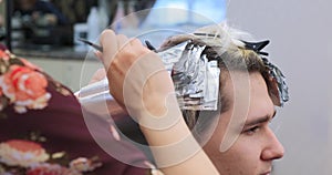 Professional hairdresser applies hair bleach with brush