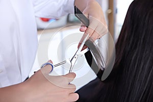 Professional hairdresser cutting woman`s hair in beauty salon, closeup