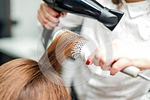 Professional hairdresser dries hair with hairdryer