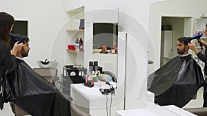 Professional hairdresser drying hair in beauty salon. Male young customer and female barber