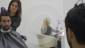 Professional hairdresser drying hair in beauty salon. Male young customer and female barber. close up