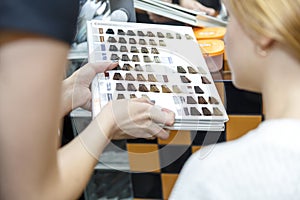 Professional hairdresser dyeing hair of her client in salon. woman choosing color with hair colorpalette. Selective