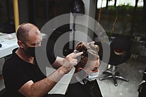 Professional hairdresser dyeing hair of his client in salon. Haircutter cutting hair
