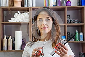 Professional hairdresser girl with comb and scissors in hands in beauty salon