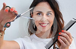 Professional hairdresser girl with comb and scissors in hands on light background