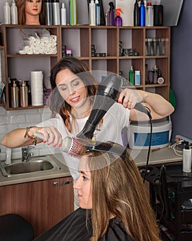 Professional hairdresser girl drying hair hairdryer and comb. Process of hair styling in beauty salon