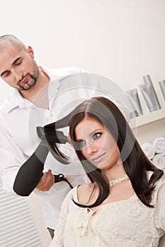 Professional hairdresser with hair dryer at salon