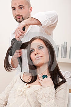 Professional hairdresser with hair dryer at salon