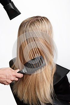 Professional hairdresser with hairdryer and hairbrush drying fem