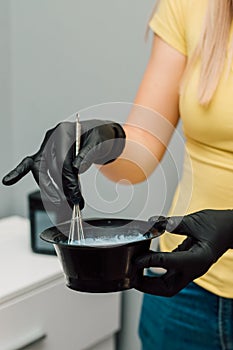 A professional hairdresser mixes a dye with an oxidizer. Hair coloring