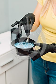 A professional hairdresser mixes a dye with an oxidizer. Hair coloring