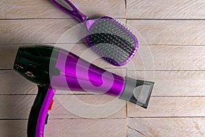 Professional hairdresser's set on white woodeb table, top view. Hairdryer, hair and combs