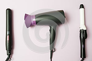 Professional hairdresser set, hair dryer, curling iron, straightener in black on purple background