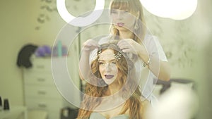 Professional hairdresser stylist salon fixing pearl tiara jewelry hair accesory diadem on blonde wavy female model head