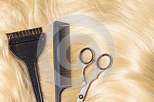 Professional hairdresser tools, scissors and comb on golden blonde hair background