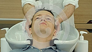 Professional hairdresser washing hair to her handsome client.