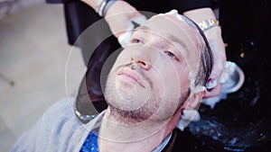 Professional hairdresser washing hair to her handsome client