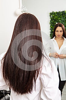 Professional hairdresser washing hair of young woman in beauty salon