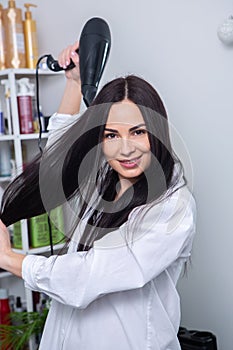 Professional hairdresser washing hair of young woman in beauty salon