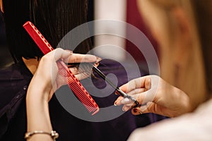 Professional hairdresser woman with comb and scissors in her hands.
