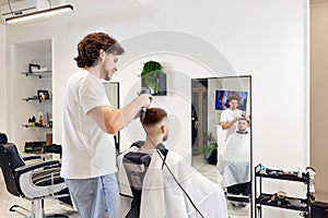 Professional hairdresser during work with man client with hair dryer