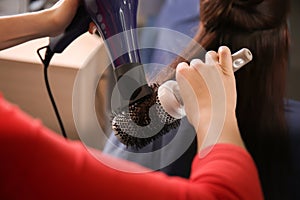 Professional hairdresser working with client in beauty salon, closeup