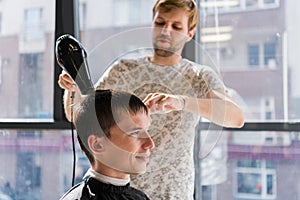 Professional hairdressing. Shot of a hairdresser drying hair with blow dryer of man client